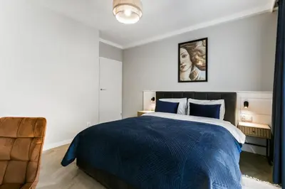 a bedroom with a blue bed and a chair at Metropolis Design Apartments in Kraków