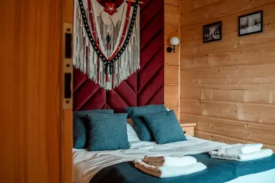 a bedroom with a bed with blue pillows and a wall at Makowy Zakątek in Maków Podhalański