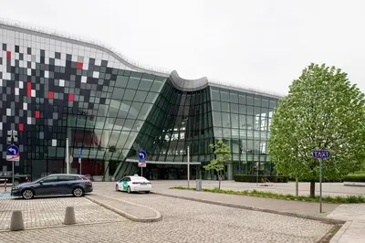 a large glass building with cars parked in a parking lot at Comfort Apartment in great location in Kraków