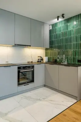 a kitchen with white cabinets and a green tiled wall at High standard in top location in Kraków