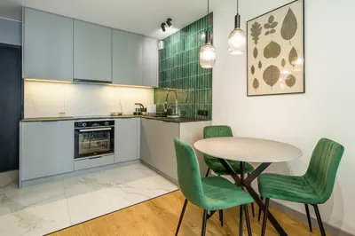a kitchen with a table and four green chairs at High standard in top location in Kraków