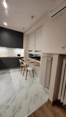 a kitchen with white marble floors and a table and chairs at Nowa Huta 12 in Kraków