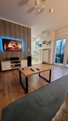 a living room with a table and a tv on a wall at Nowa Huta 12 in Kraków