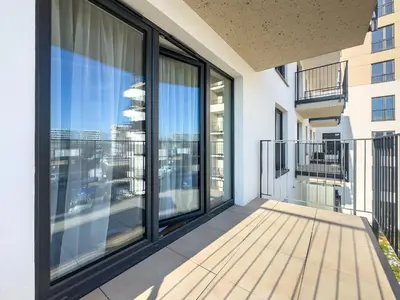 a balcony with large windows and a view of the city at Nowoczesny Apartament Pychowicka 3B in Kraków