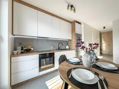 a kitchen with a wooden table and white cabinets at Nowoczesny Apartament Pychowicka 3B in Kraków