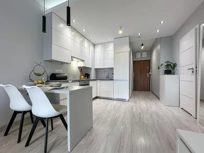 a kitchen with white cabinets and a table and chairs at Krakowski zakątek- Apartament premium z garażem in Kraków