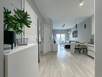 a white kitchen and living room with a dining room at Krakowski zakątek- Apartament premium z garażem in Kraków