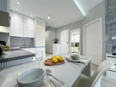 a kitchen with white cabinets and a table with a bowl of fruit at Krakowski zakątek- Apartament premium z garażem in Kraków