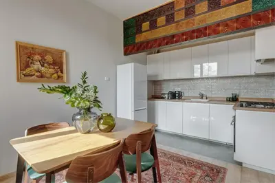 a kitchen with white cabinets and a wooden table and chairs at Basztowa 5a in Kraków