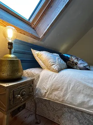 a bed with pillows and a lamp on a night stand at Szumidomki strefa z jacuzzi sauna widok na potok las in Zawoja