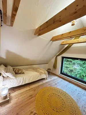 a bedroom with a bed and a large window at Szumidomki strefa z jacuzzi sauna widok na potok las in Zawoja