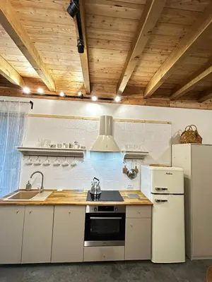 a kitchen with white appliances and wooden ceilings at Szumidomki strefa z jacuzzi sauna widok na potok las in Zawoja