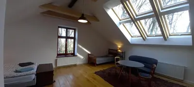 an attic room with a bed and a table and windows at Nowy Dwór w Goszycach in Goszyce