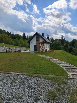 a small white building in the middle of a field at Domek pod lasem in Toporzysko