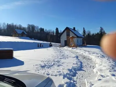 a road covered in snow in front of a house at Domek pod lasem in Toporzysko