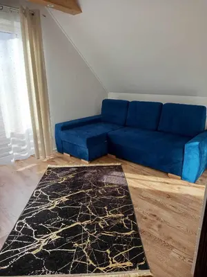 a blue couch in a living room with a rug at Domek pod lasem in Toporzysko