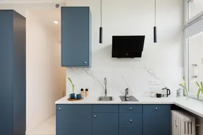 a kitchen with blue cabinets and a tv on the wall at Azure Haven Old Town Apartament in Kraków