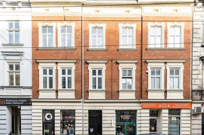 a brick building with white windows on a street at Starowiślna 38 Charming Apartment by BookingHost in Kraków