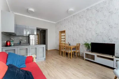 a living room with a red couch and a kitchen at Starowiślna 38 Charming Apartment by BookingHost in Kraków