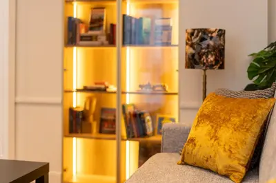 a yellow book shelf in a living room with a couch at Heritage Apartments in Kraków