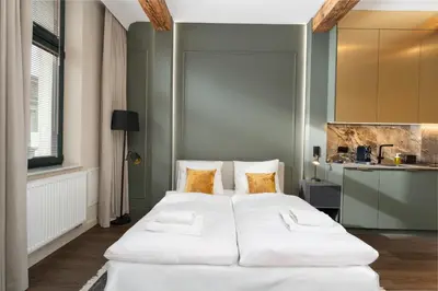 two white beds in a room with a kitchen at Heritage Apartments in Kraków