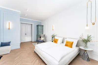 a white bedroom with a large white bed and a couch at Heritage Apartments in Kraków
