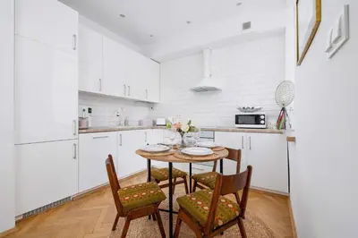 a white kitchen with a table and chairs at Słoneczny Apartament 2 Sypialnie, Biurko & Klimatyzacja by Rent like home in Kraków