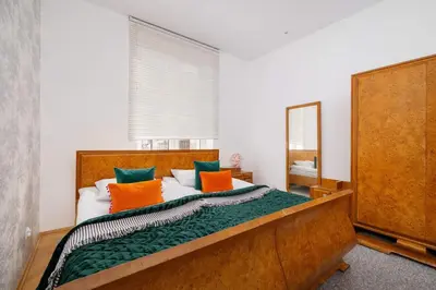 a bedroom with a bed with orange and green pillows at Słoneczny Apartament 2 Sypialnie, Biurko & Klimatyzacja by Rent like home in Kraków