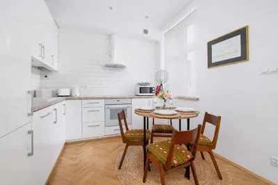 a white kitchen with a table and chairs in it at Słoneczny Apartament 2 Sypialnie, Biurko & Klimatyzacja by Rent like home in Kraków