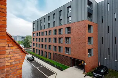 a red brick building with cars parked in a parking lot at Apartment Cracow Wawrzyńca by Noclegi Renters in Kraków