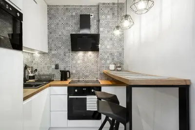 a kitchen with white cabinets and a black stove at Apartment Cracow Wawrzyńca by Noclegi Renters in Kraków