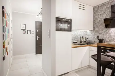 a white kitchen with white cabinets and a counter at Apartment Cracow Wawrzyńca by Noclegi Renters in Kraków