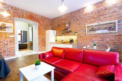 a red couch in a living room with a brick wall at Apartamenty Łazarza 17 in Kraków
