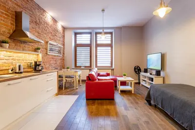 a kitchen and living room with a red couch and a bed at Apartamenty Łazarza 17 in Kraków
