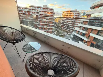 a balcony with two chairs and a view of buildings at Wiślane Tarasy 2 VIP Apartamenty JACUZZI in Kraków