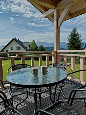 a patio table and chairs on a deck with a view at Plutowka in Zawoja