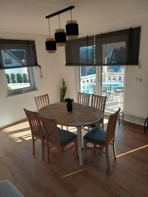 a dining room with a table and chairs and windows at Plutowka in Zawoja