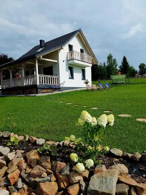 a white house with a balcony and a yard at Plutowka in Zawoja