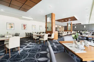 a restaurant with wooden tables and white chairs at DoubleTree by Hilton Krakow Hotel & Convention Center in Kraków