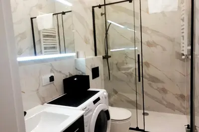 a bathroom with a washing machine and a shower at Skawińska Street Apt in Kraków