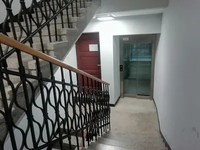 a hallway with a staircase and a red door at Skawińska Street Apt in Kraków