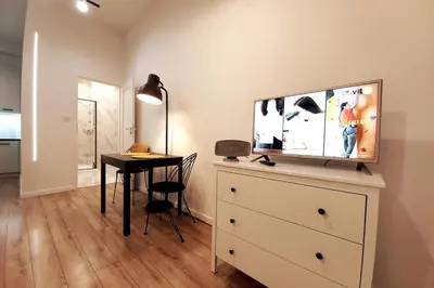 a room with a dresser with a tv and a table at Skawińska Street Apt in Kraków