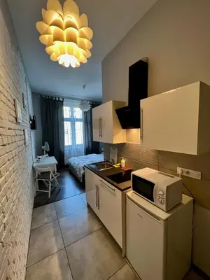 a kitchen with a microwave and a room with a bed at AMETYST Apartment in Kraków