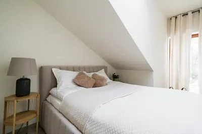 a white bedroom with a white bed and a window at Apartament Park Zdrojowy 11 - NOWOŚĆ in Rabka