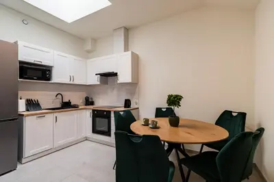 a kitchen with a wooden table and green chairs at Apartament Park Zdrojowy 11 - NOWOŚĆ in Rabka