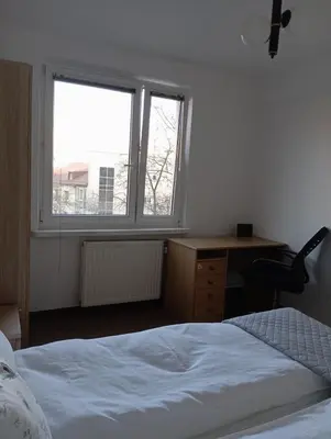 a bedroom with a bed and a desk and a window at Królewska in Kraków