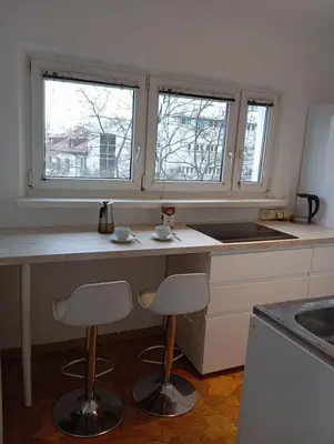 a kitchen with two bar stools and two windows at Królewska in Kraków