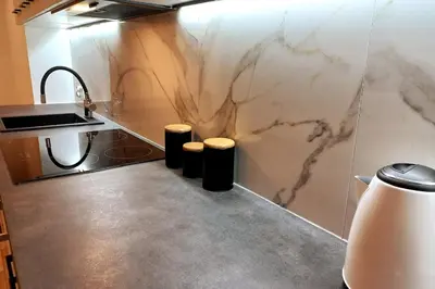 a kitchen with a marble wall with a sink and stools at Apartment by Wawel castel - G1a in Kraków