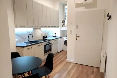 a kitchen with white cabinets and a table with chairs at Apartment by Wawel castel - G1a in Kraków