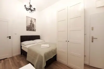 a small white bedroom with a bed and a chandelier at Cozy apartment by Wawel castel - G1b in Kraków